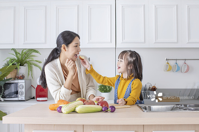 美女妈妈和可爱女儿在厨房吃健康食物图片素材