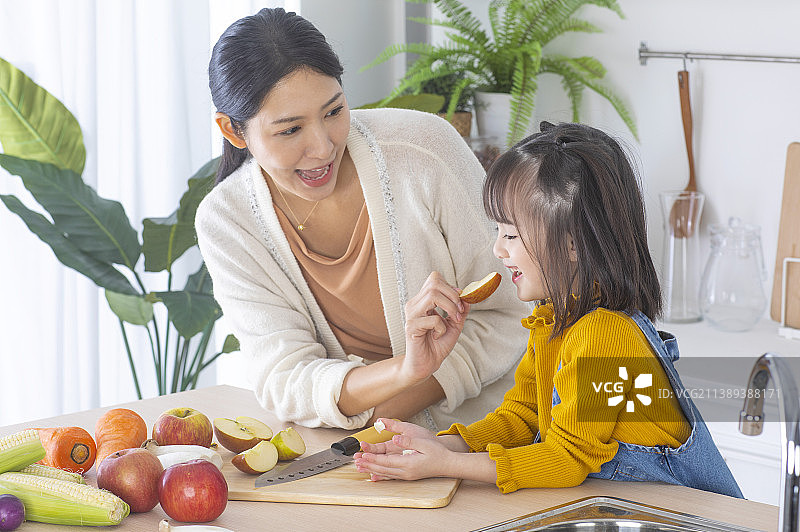 美女妈妈和可爱女儿在厨房吃健康食物图片素材