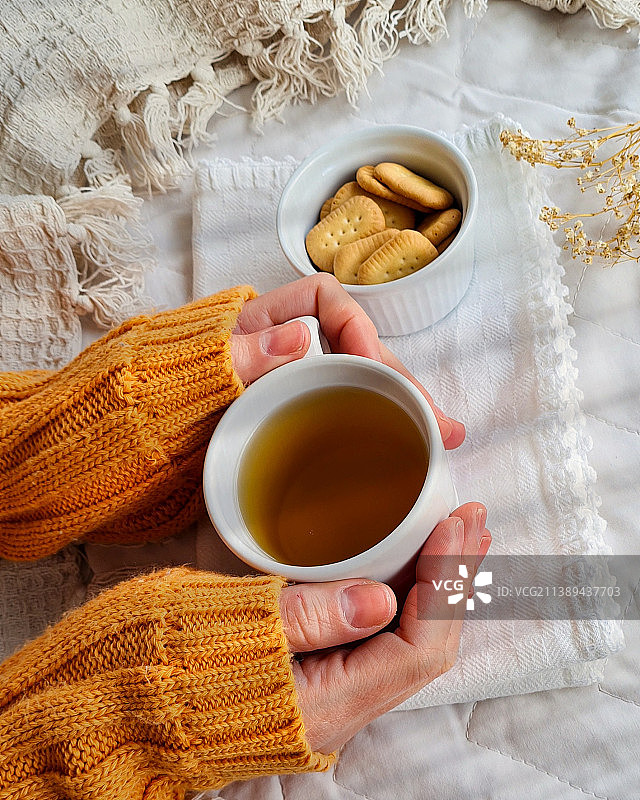 女人在亚麻布上端着茶杯的局部特写图片素材