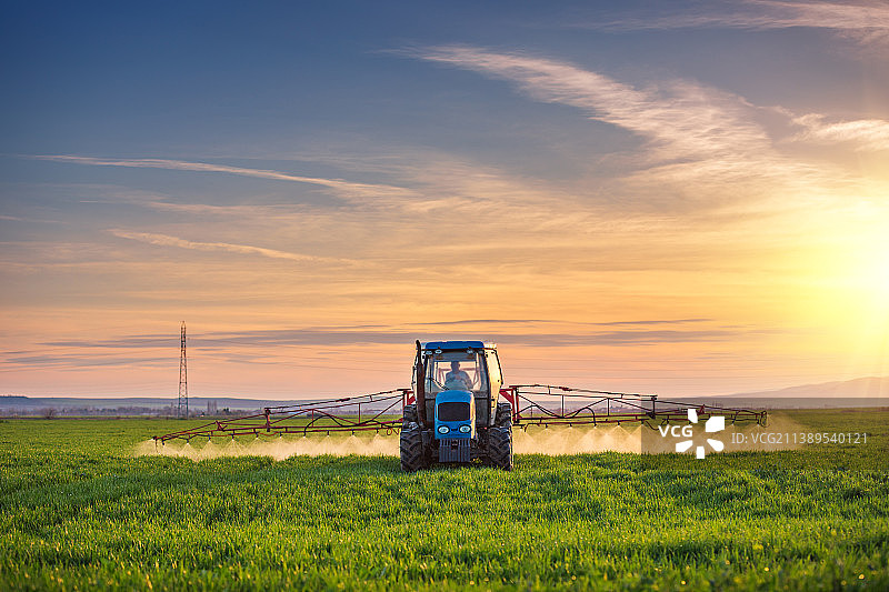 拖拉机在绿色田野上喷洒农药化肥，农业背景概念图片素材
