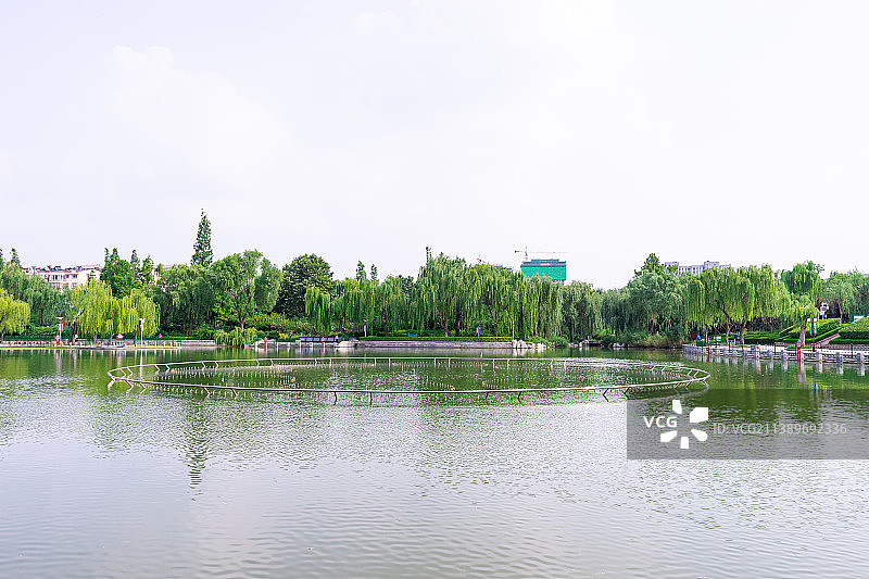 中国山东省泰安市东湖公园的池塘，水面上的喷泉设备和蓝色白云图片素材