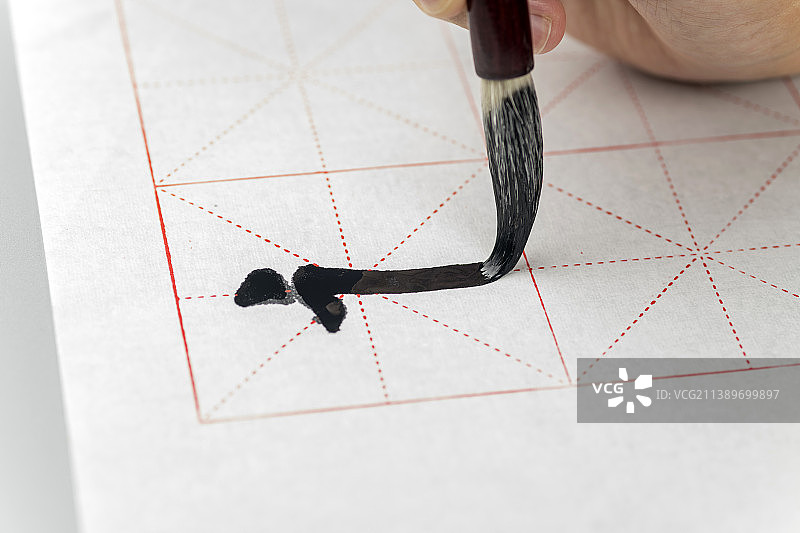 手持毛笔写毛笔字书法特写灰色背景图片素材