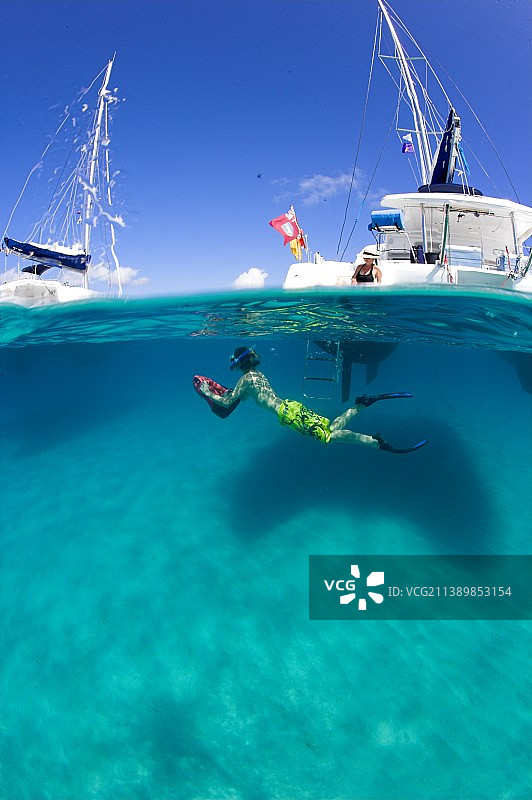 男孩在帆船附近浮潜图片素材