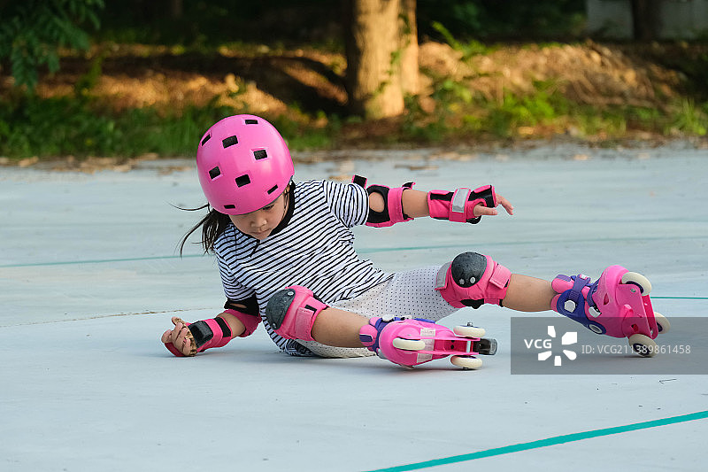 可爱的亚洲小女孩在泰国公园练习轮滑，佩戴护具和安全头盔图片素材