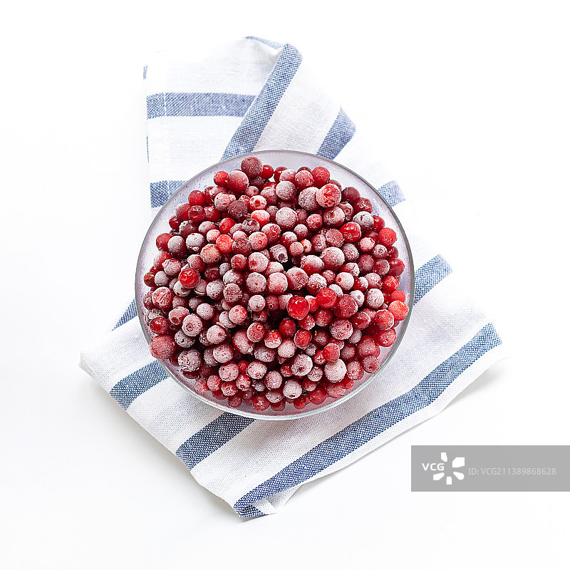 俄罗斯，白色条纹餐巾玻璃碗中的冰冻森林越橘图片素材