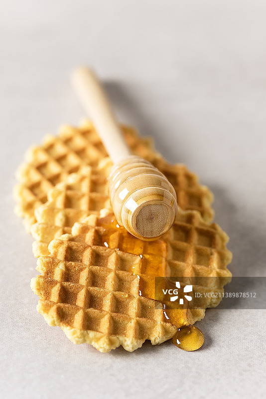 蜂蜜淋在新鲜华夫饼早餐上，搭配比利时华夫饼灰色背景竖版图片素材