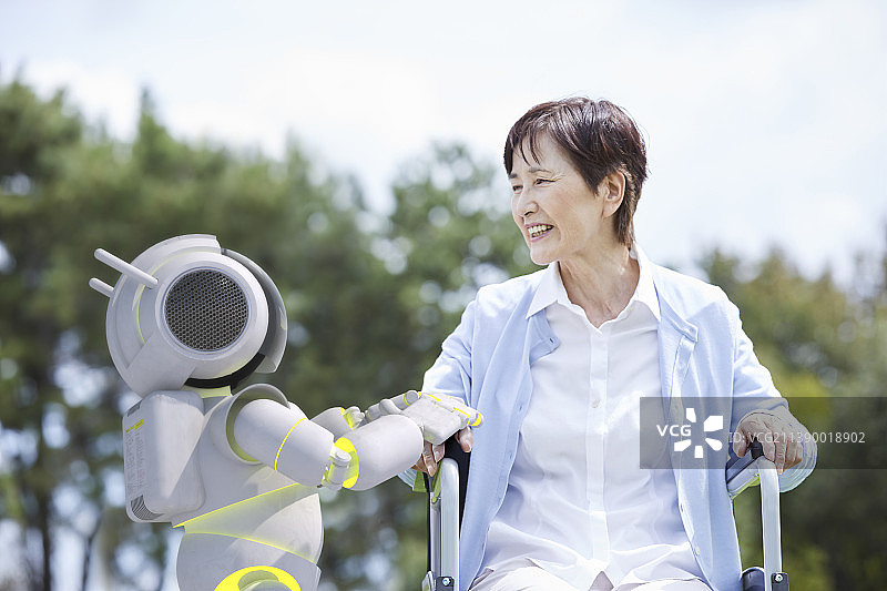 坐在轮椅上的年长妇女和护理机器人图片素材