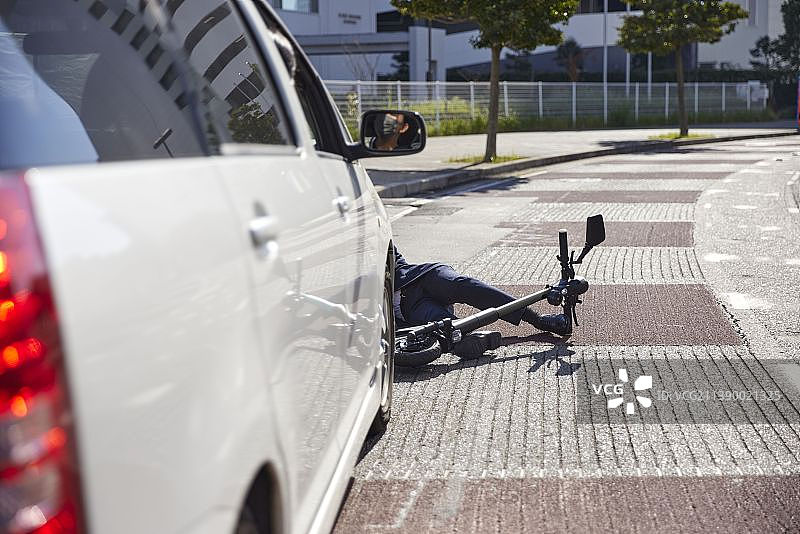 骑电动滑板车被汽车撞倒的男人图片素材