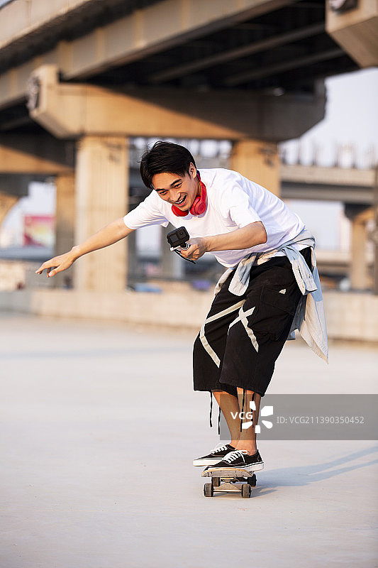 年轻男子滑滑板并用Gopro拍摄图片素材
