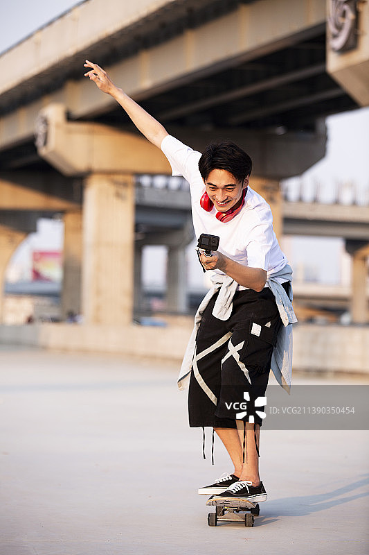 年轻男子滑滑板并用Gopro拍摄图片素材