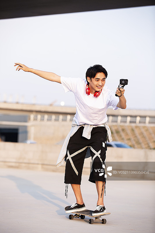 年轻男子滑滑板并用Gopro拍摄图片素材