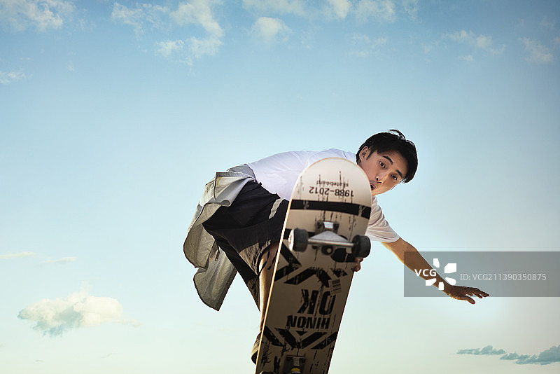 年轻男子滑滑板做极限动作图片素材
