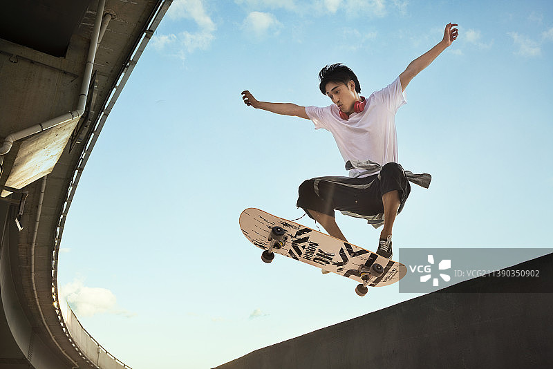年轻男子滑滑板做极限动作图片素材