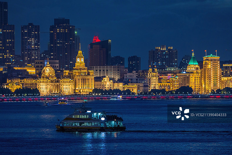 黄浦江上轮渡驶过，对岸的外滩万国建筑群的泛光照明。图片素材