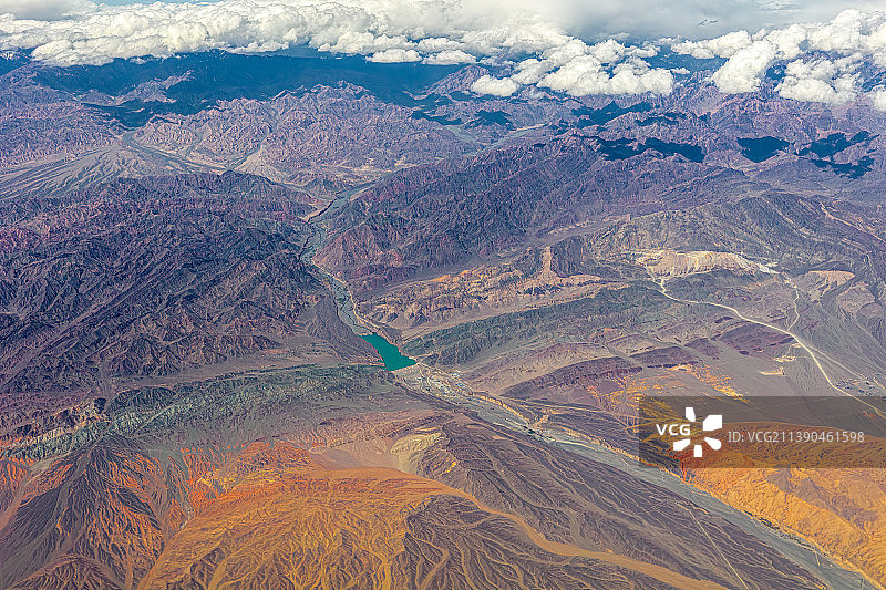 新疆乌鲁木齐附近航拍山脉，水库像绿宝石一样镶嵌在褶皱起伏的丘陵中，铜矿铁矿露出地表，呈现艳丽的红黄色图片素材