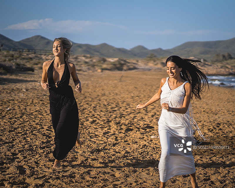 穿比基尼在海滩日落时度过一天的两个女孩图片素材