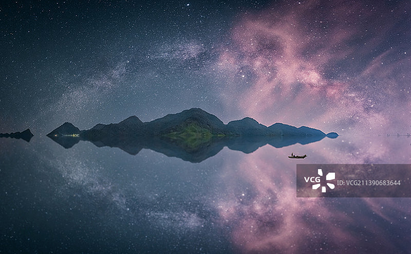 山顶的银河拱桥和倒影，水里有一个人在泛舟图片素材