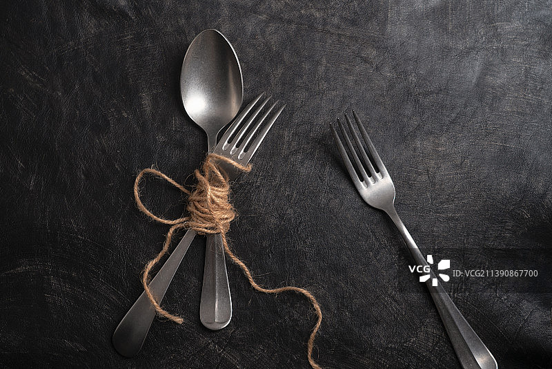 暗调黑色质感背景下被麻绳捆绑的叉子勺子图片素材