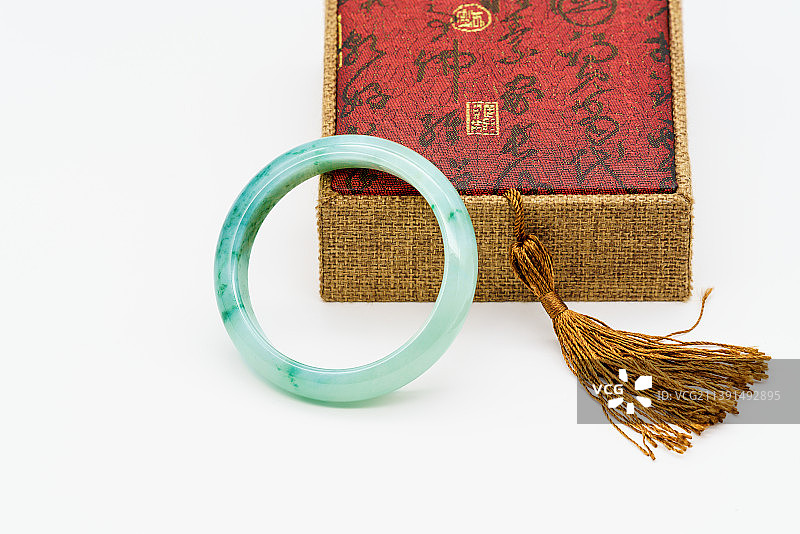 翡翠首饰，一只翠绿色的玉镯，配着带有金色流苏的盒子图片素材