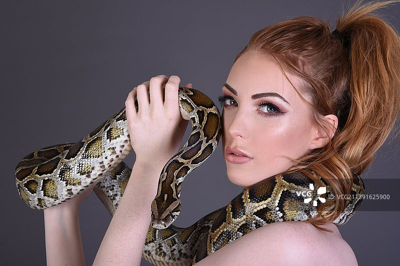 抱着宠物蛇的迷人红发模特，英国沃金厄姆图片素材