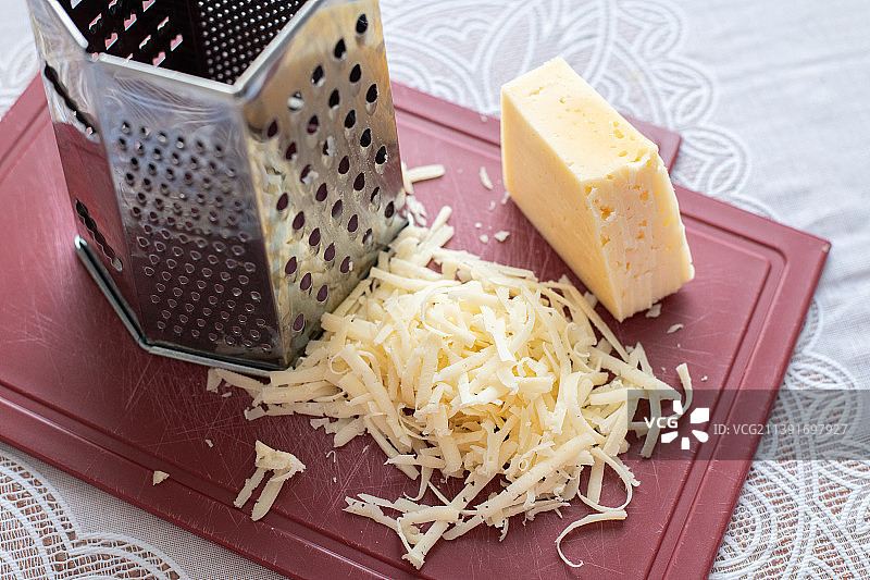 刨丝器旁的塑料板上堆放着磨碎的奶酪图片素材