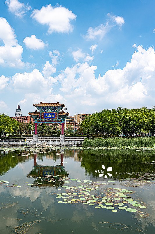 蓝天白云背景映衬下的山东济宁南池公园古南池牌坊倒影风光图片素材