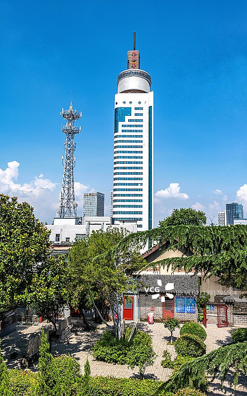 山东济宁太白楼上看城市天际线.蓝天白云下的济宁通讯大厦济宁地标建筑风光图片素材