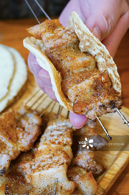 鲁菜起源地之一淄博有经典菜系博山菜，烧烤也是当地美食。淄博烧烤配小饼、香葱、甜面酱，小饼卷肉十分美味图片素材