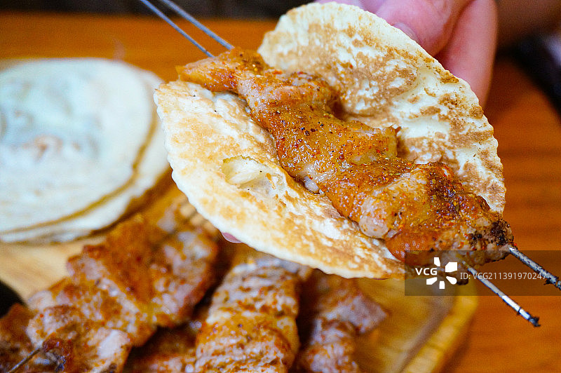 鲁菜起源地之一淄博有经典菜系博山菜，烧烤也是当地美食。淄博烧烤配小饼、香葱、甜面酱，小饼卷肉十分美味图片素材