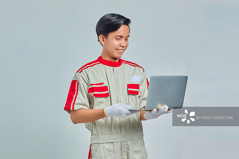 笑容满面、穿着制服的帅气机械师正在使用笔记本电脑图片素材