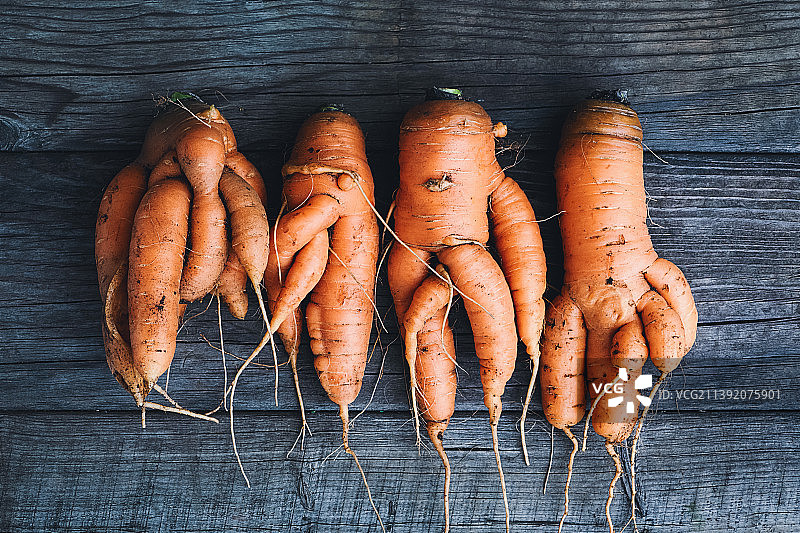畸形蔬菜：木桌上扭曲的胡萝卜图片素材