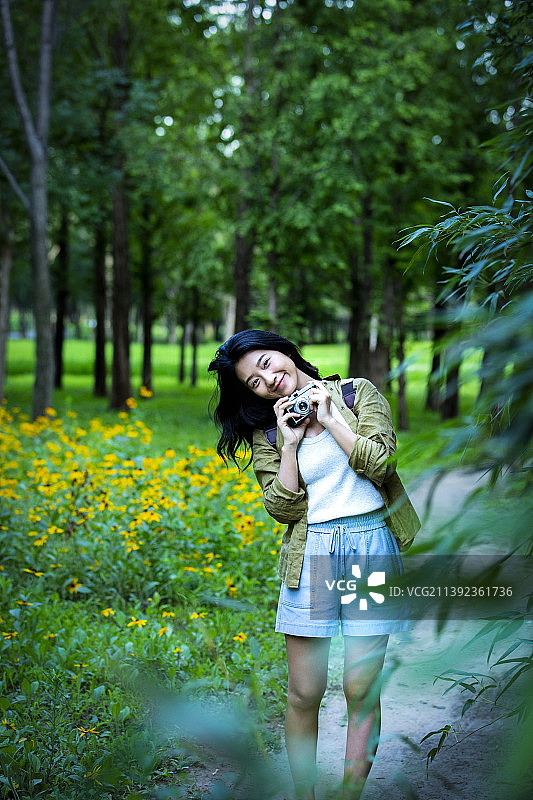 青年女子拿着相机在公园游玩度假，享受大自然图片素材