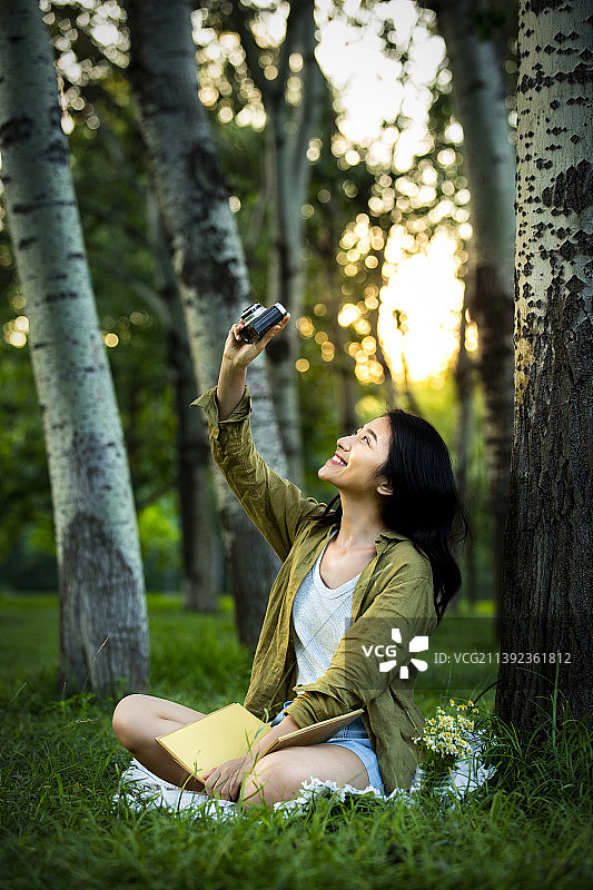 青年女子在公园野餐郊游，看书拍照图片素材