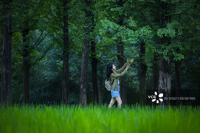 青年女子拿着装满小花的篮子在郊区游玩，享受大自然图片素材