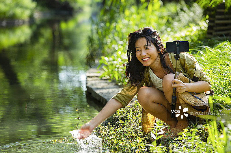 青年女子在公园河边玩水嬉戏图片素材