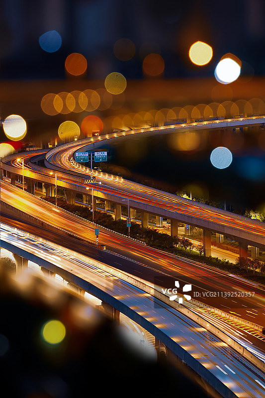 夜晚城市车流灯光光斑散光中的高架立交与建筑图片素材