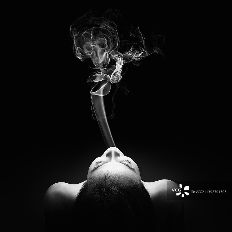 女人在黑色背景下吸烟的特写图片素材