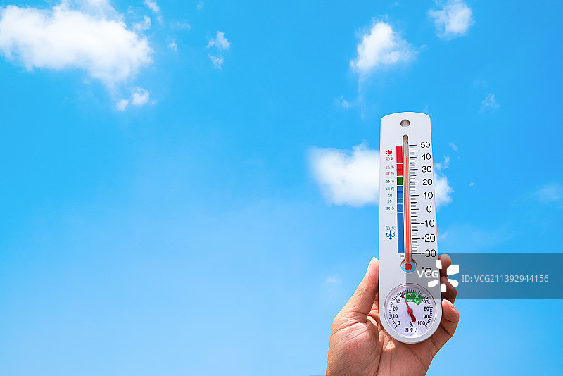 蓝天白云下手持（拿着）温度计,夏季高温炎热酷暑环境保护概念图片图片素材