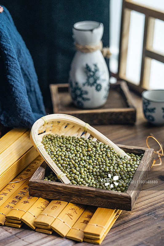 簸箕中盛满绿豆，放在书简上，中国风摆盘图片素材