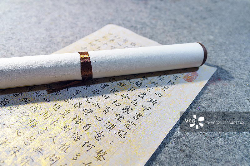 书案上的一幅汉字书法作品、卷轴、毛笔和镇纸图片素材