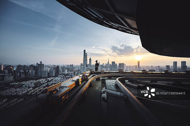 城市风光摄影师爬楼党无人机航拍飞手在楼顶拍摄记录上海城市日落风光图片素材