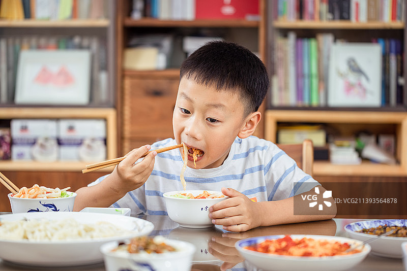 中国男孩夏天在家里吃打卤面图片素材