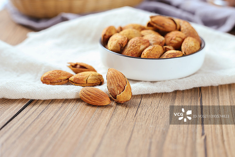原木色桌面上的一小碟巴旦木扁桃仁图片素材