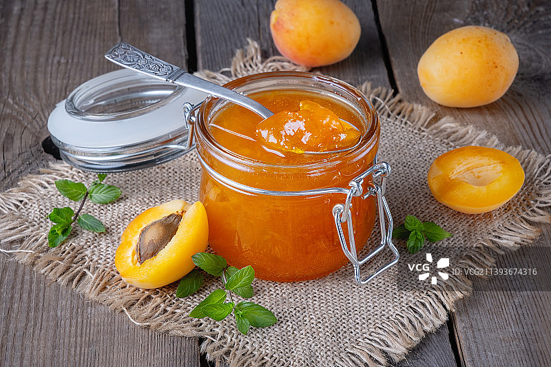 旧木桌上的玻璃罐装杏子果酱图片素材