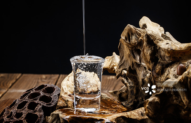 向木板上摆放的酒具内倒入清澈的白酒酒花图片素材