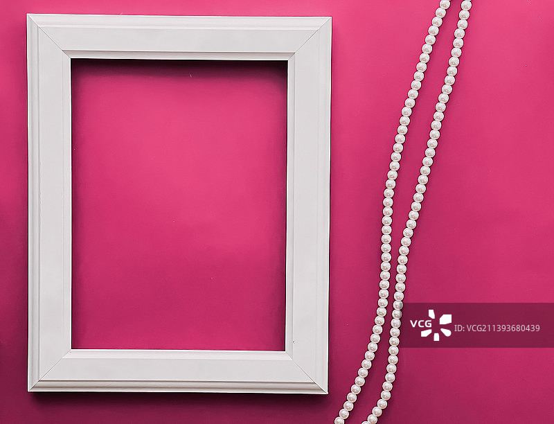 白色竖版艺术画框和粉色背景上的珍珠首饰图片素材