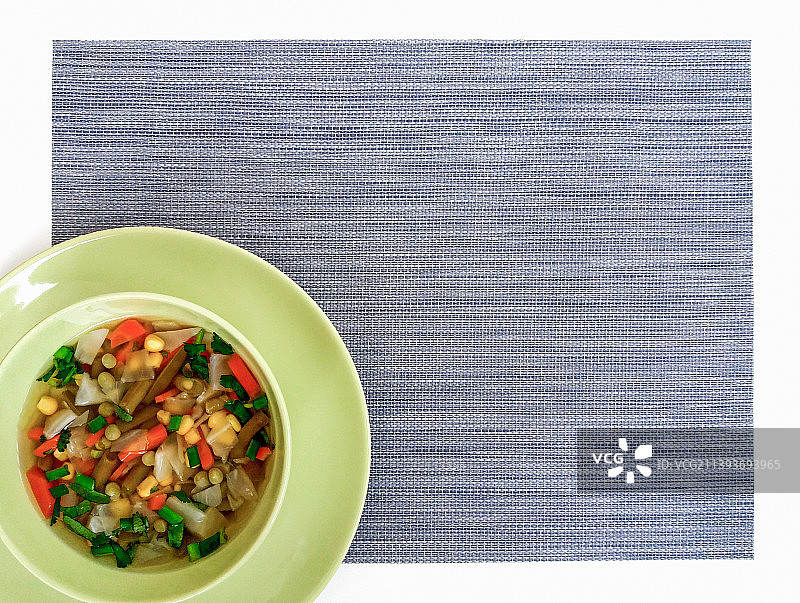 绿色碗蔬菜汤，灰色餐垫，顶部视角，留白图片素材