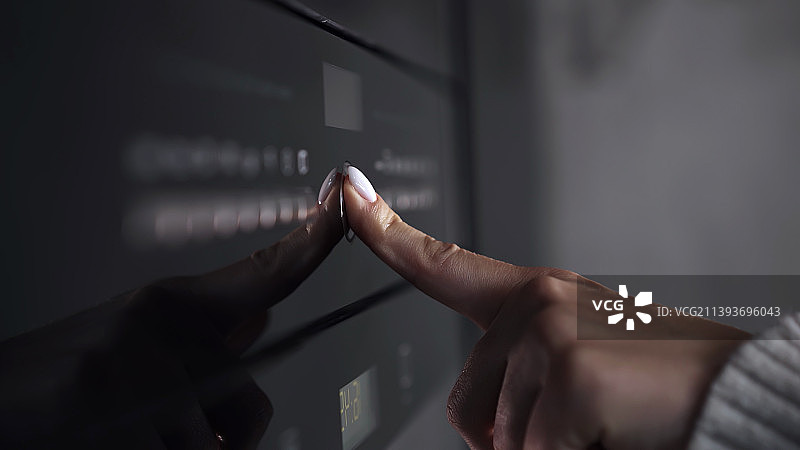 女人的手指按下现代燃气灶或烤箱上的按钮图片素材