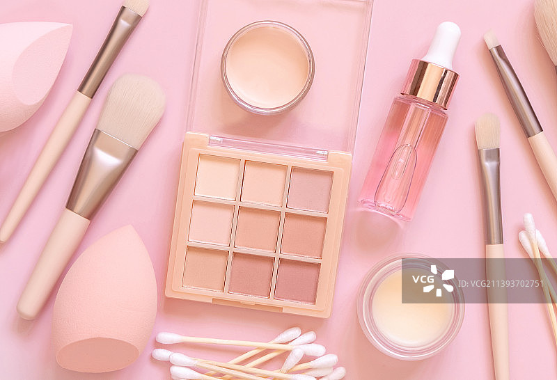 浅粉色背景上的自然米色眼影和装饰性化妆品，顶视图图片素材