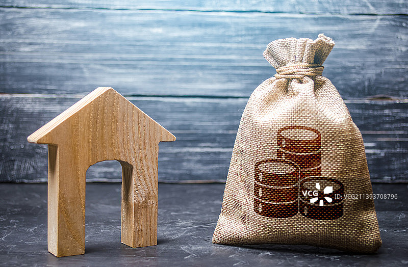 木质背景上的钱袋与房屋模型特写图片素材